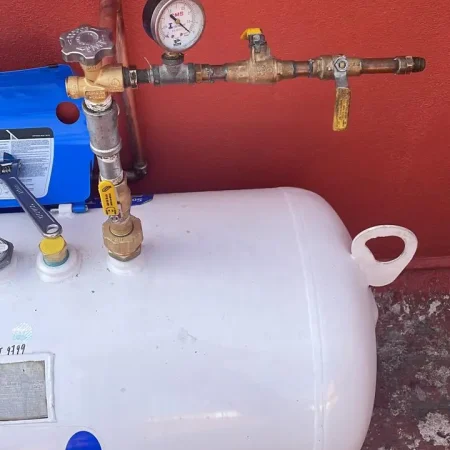 Tanque estacionario de gas pintado de blanco instalado en azotea con conexión de seguridad en color amarillo.